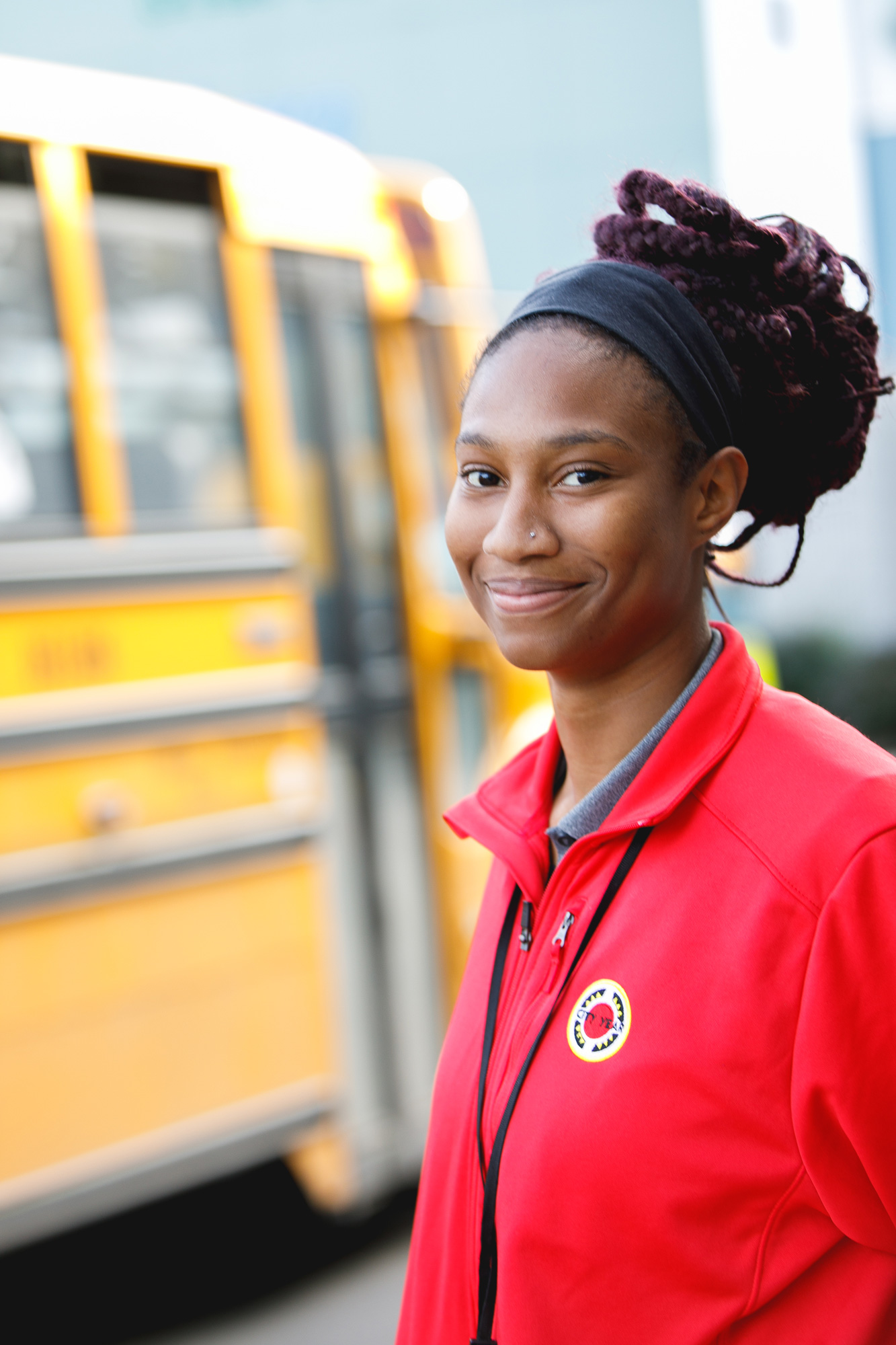 female americorps volunteer standing in front of school bus